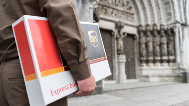 UPS delivery driver carrying an UPS express box on the street