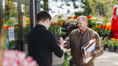 Male UPS driver dropping a package off to a male at a flower shop