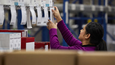 Female sticking labels on a wire shelf holding packages