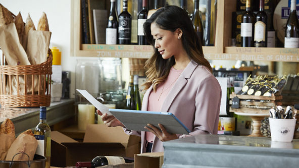 Female checking a paper and holding a tablet in a wine shop