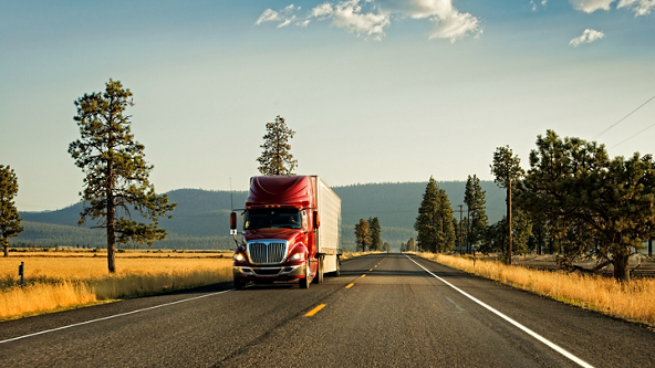 Semi-truck driving down an empty country road 