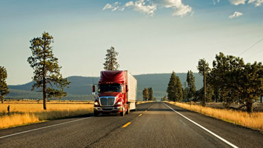 Semi-truck driving down an empty country road 