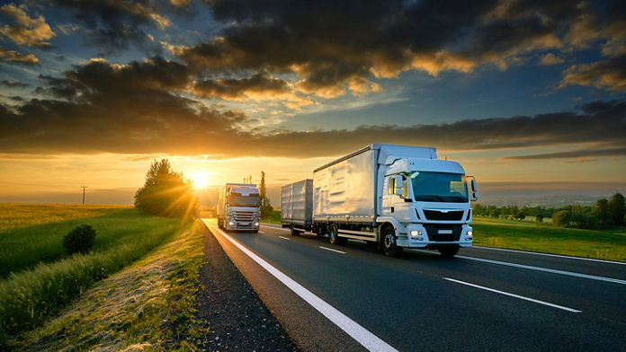 Two semi-trucks driving down an empty country rode