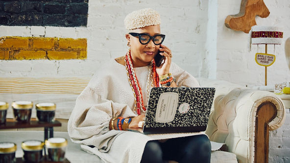 woman with laptop holding a phone