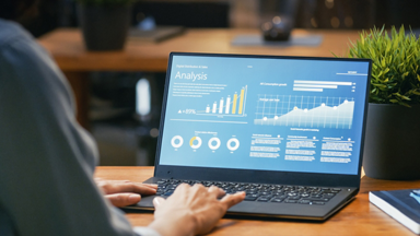 Hands on a laptop with analysis graphs on the screen 