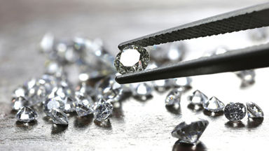 Tweezers holding a diamond with multiple diamonds on the table