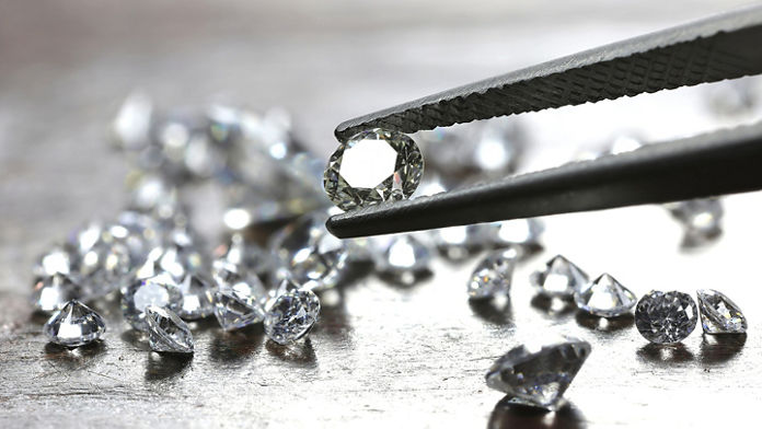 Tweezers holding a diamond with multiple diamonds on the table