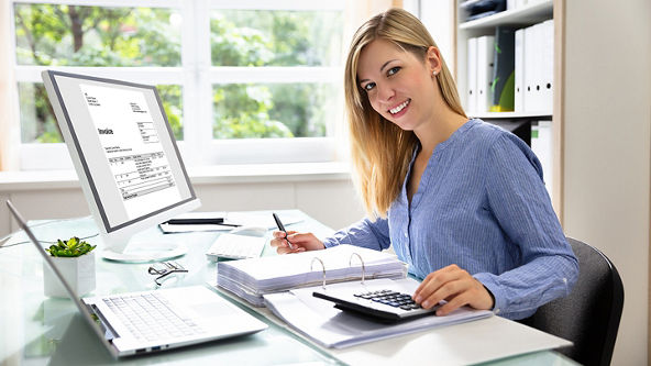 Female sitting at a desk with an open binder and calculator 