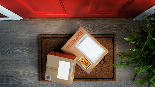 Two packages sitting on a welcome mat in front of a door 