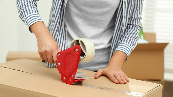 Close up of hands closing a box with packing tape