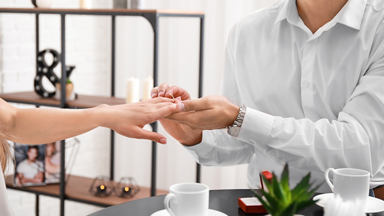 Man placing a ring on woman's finger