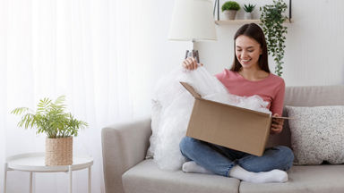 Female opening a cardboard box from her couch