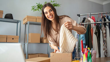Female pulling a cream knit scarf out of a box 