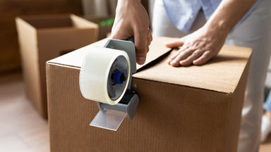 Close up of hands closing a box with packing tape