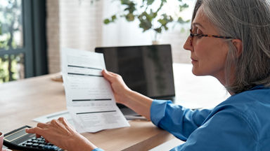 Female holding a piece of paper and using a calculator