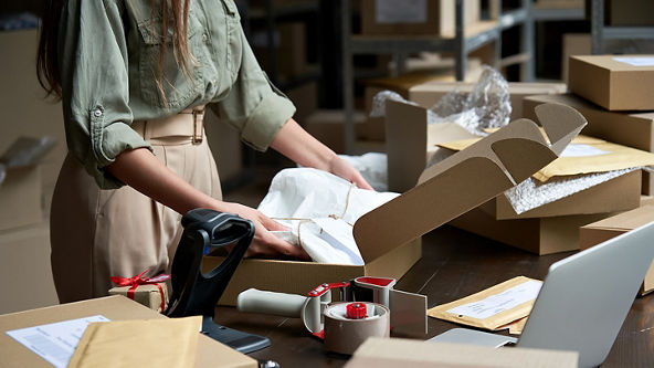 Female placing an item wrapped in white tissue paper into a box
