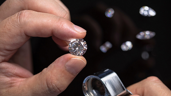 Close up of hands holding a round cut diamond 