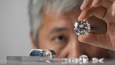 Male jeweler holding up a large diamond to inspect 