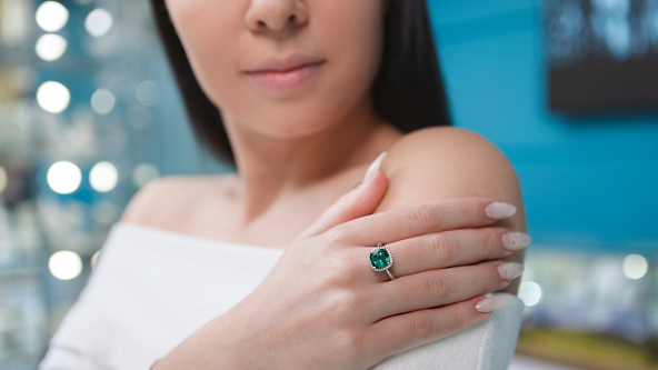 Close up of a female wearing a diamond and green gemstone ring 