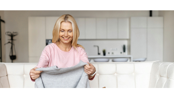 Woman looking at a sweater she pulled from a box 