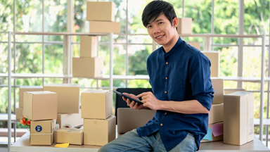 Male using a tablet while surrounded by boxes 