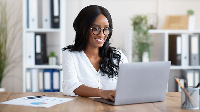 Female typing on her laptop on a desk in a home office 