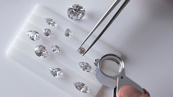 Tweezers holding a diamond with multiple diamonds on the table