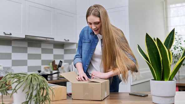 Female opening a box on her kitchen counter. 