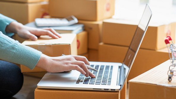 Close up of a female using a laptop with her other hand resting on a box