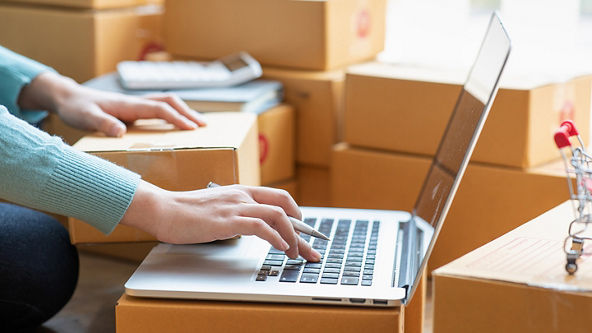 Close up of hands using a laptop surrounded by boxes 