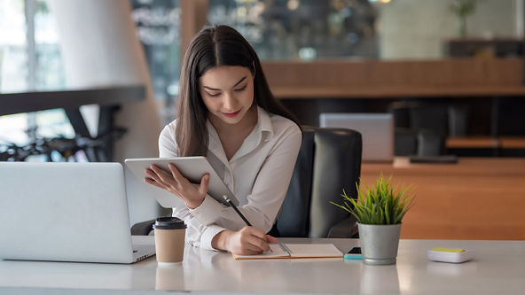 Female holding a tablet while taking notes