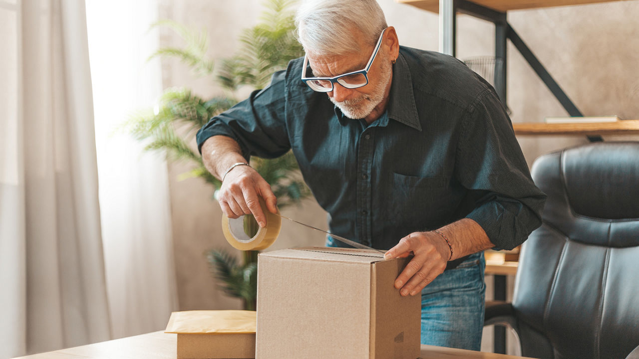 Male taping a box closed in a home office 