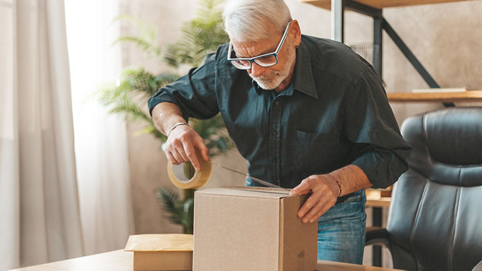 Seal the parcel. A grown man sends a box of goods by mail. Return of purchase to the online store.; Shutterstock ID 1975106429; purchase_order: N/A; job: ; client: ; other: 