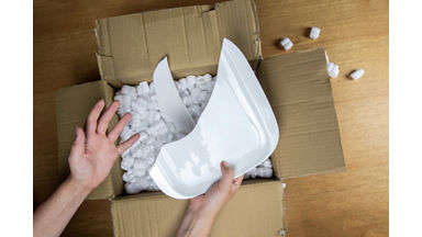 Broken plate in damaged cardboard box top view, damaged home delivery unpacking box close up