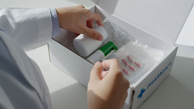 Close up of a pharmacist pulling medicine from a pharmacy box