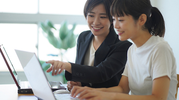 Female pointing at the laptop screen of the female next to her