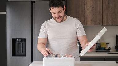 Male in a kitchen pulling fish from a foam ice box
