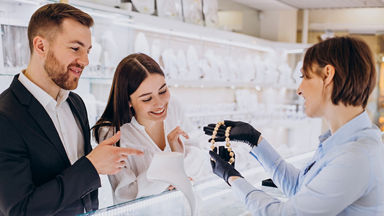 Female jeweler showing a necklace to a male and female in a jewelry store