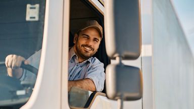 Male truck driver smiling and looking out the window 