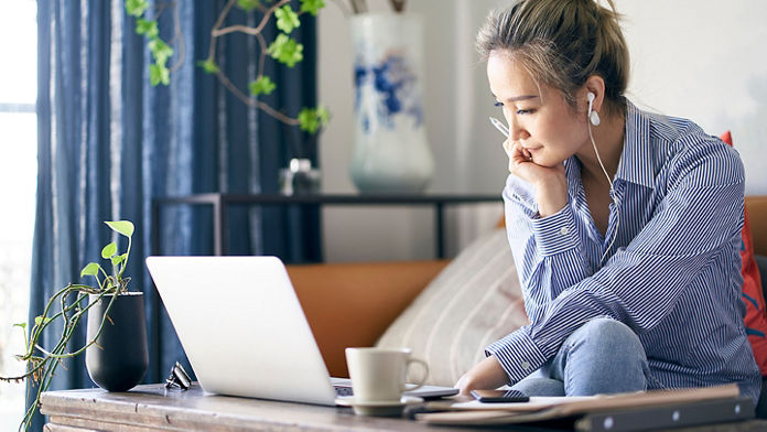 Female sitting on the couch as she looks at a laptop