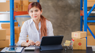 Female sitting at a table with a tablet and packages 