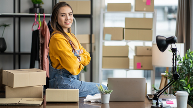 Asian female sitting on a desk with boxes around her