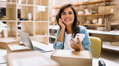 Female holding her smart phone and sitting at a desk with boxes