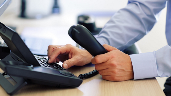 Close up of a male dialing an office phone 