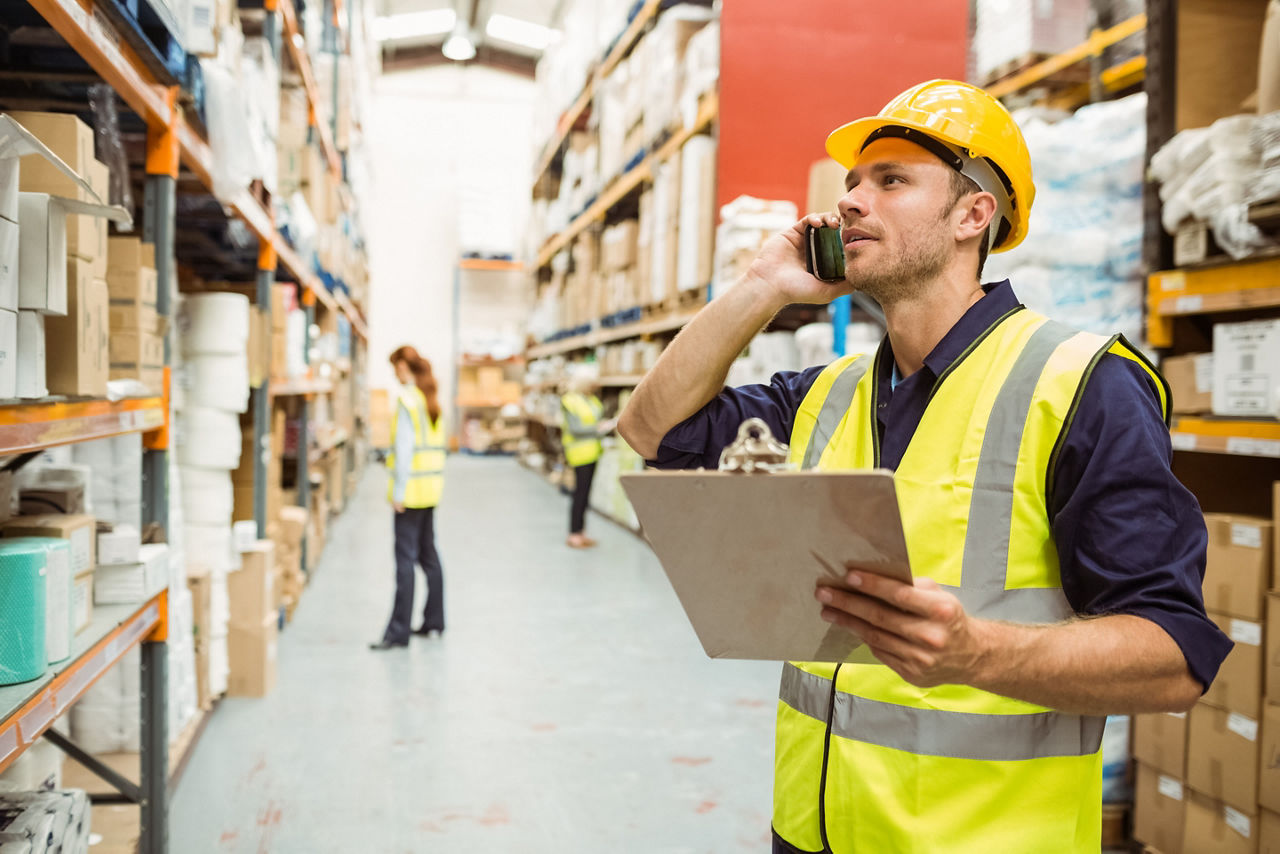 Warehouse worker talking on the phone holding clipboard in a large warehouse; Shutterstock ID 252244078; purchase_order: Channel Partner; job: ; client: ; other: 