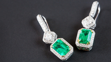 Diamond and green gemstone earrings on a black background 