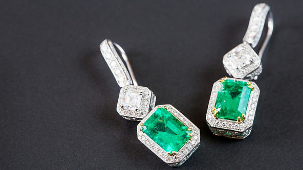 Diamond and emerald earrings on a black background