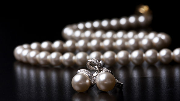 Pearl earrings and necklace on a black background