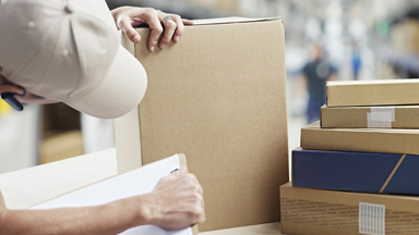 Male looking at a box and holding clip board