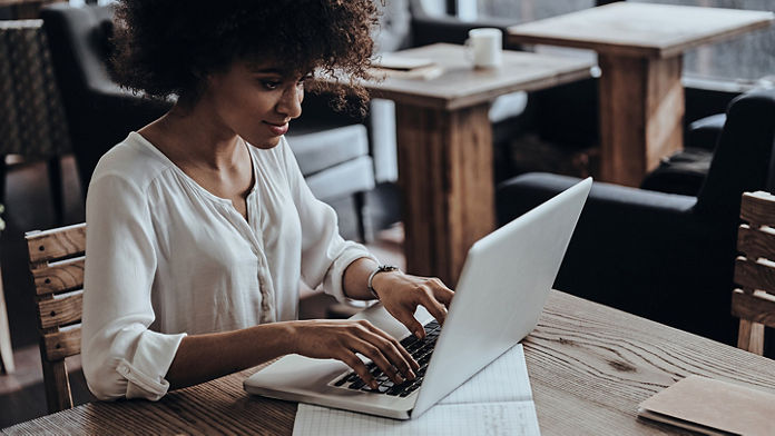 Female typing on her laptop at a café table 